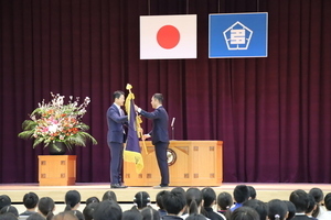 写真：笠原小中学校開校式で市長から校長へ新しい校旗が授与される様子