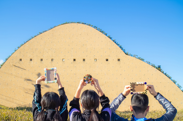 第7回フォトコンテスト受賞作品(モザイクタイルミュージアムを前にタイルフレームを持つ三人の子供の写真)