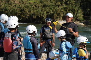 写真:川岸でインストラクターの説明を聞く子どもたち