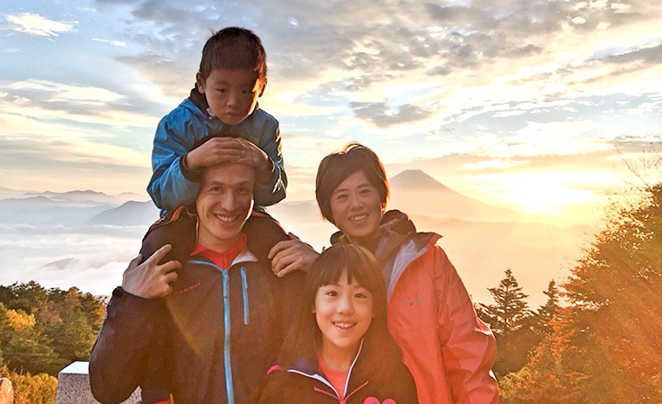 夕暮れのなか山を背景に撮影した記念写真